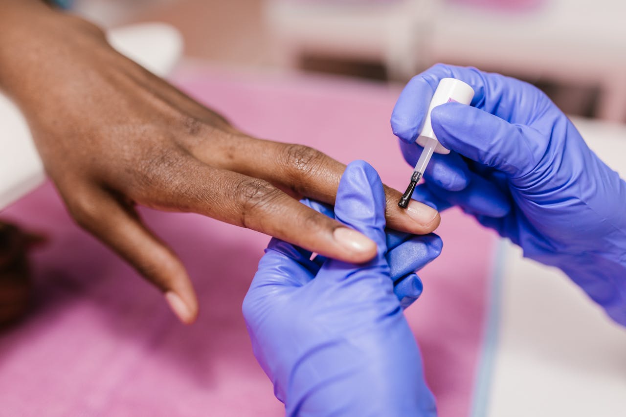 A close-up of a manicure in progress, featuring nail polish application on fingernails in a salon.
